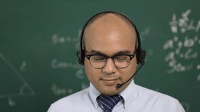 Young asian teacher man teaching video conference with student. Male Indian teacher training the mathematics in classroom from online course. He wearing small talk headset.