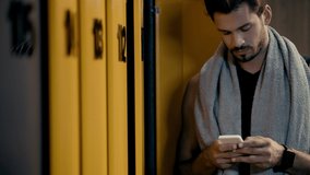 cheerful sportsman using smartphone in locker room