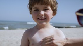 Mother Applying Sunblock Cream on Kid. Mom Applying Sunscreen Lotion on Body Son at Beach. Mother Preparing Child for Bath in Sea. Happy Family at Beach Sun Protection. Travel Summer Suntan Vacation. - Powered by Shutterstock - Get 15% off with code: PIKWIZARD15