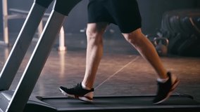 cropped view of athletic man running on treadmill in gym