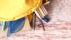 Top view of yellow backpack with different colorful stationery on table. - Powered by Shutterstock - Get 15% off with code: PIKWIZARD15