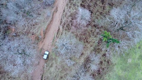 An aerial drone video of a Russian made Lada Niva 4x4 driving off road along a dirt track in Northern Albania in the winter.