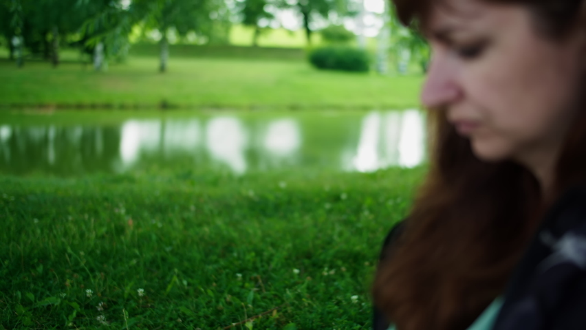 sad brunette woman sitting in the park near a tree and thinking about something, memories