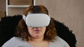 Virtual reality helmet. Woman in VR glasses. She watches video clips. The girl is surprised and delighted.