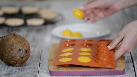 Hands taking orange filling out of a flexible silicone mold.