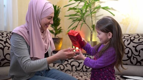 Ramadan gift box. Happy Muslim mother gives her daughter a gift for Eid Holiday