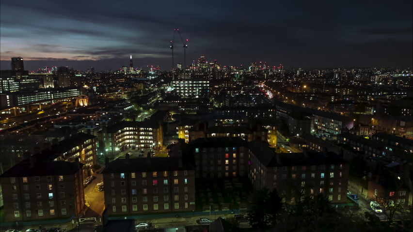 Establishing Aerial View Shot of London UK, slow crawl over East London suburbs toward center, United Kingdom at night evening