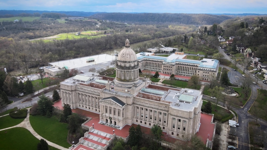 Flying away from State Capitol Building next to Kentucky river in the capital city of Frankfort during early morning overcast day