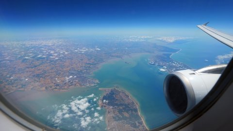 Look out through airplane window to Passage of Antioch between Isle of Rhe and Oleron Island, Bay of Biscay on Atlantic Coast of France. Jet liner engine and wing on right side at foreground