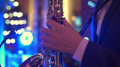 A caucasian man plays saxophone at a concert, party, music party, neon colors, playing saxophone close up, making music and improvizing at the party, wind band