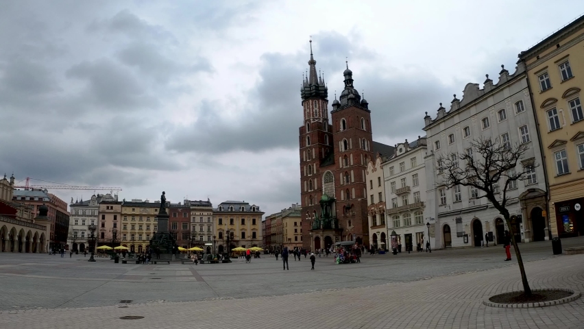 Krakow, Poland - March 27, 2020: People doing leisure activity such as walking and a girl riding bicycle at Main market square in the old town center of Cracow in European city against dramatic stormy | Shutterstock HD Video #1069784935