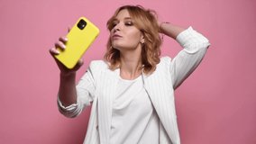 Funny trendy woman posing taking selfie use smartphone isolated on pink studio background. People lifestyle concept