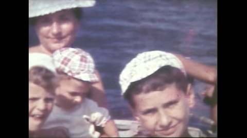 Old 8mm film of a family with mom and three kids sailing on a boat near the coast and then climbing rocks with dad FDV
