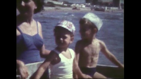 Old 8mm film of two children on a boat driven by their mom. Portraits of children of which one is eating ice cream and has a dirty mouth FDV