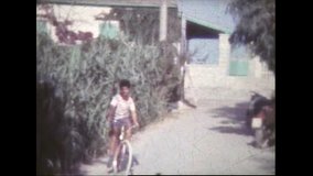 An old 8mm film of an eight year old boy pedaling on a bicycle a blond boy running and three children running along with their daddy FDV