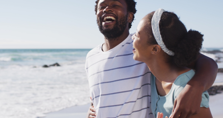 African american couple smiling, embracing and walking on the beach. healthy outdoor leisure time by the sea. | Shutterstock HD Video #1069787491