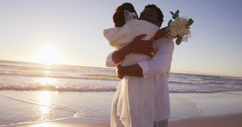 African american couple in love getting married, embracing on the beach at sunset. marriage, love and romance, holiday by the sea.