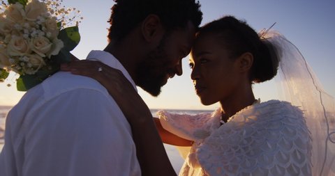 African american couple in love getting married, looking at other on the beach at sunset. marriage, love and romance, holiday by the sea.