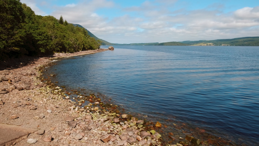 Low angle panning shot of the iconic Loch Ness in Scotland, a large, deep, freshwater loch in the Highlands extending for 37 kms