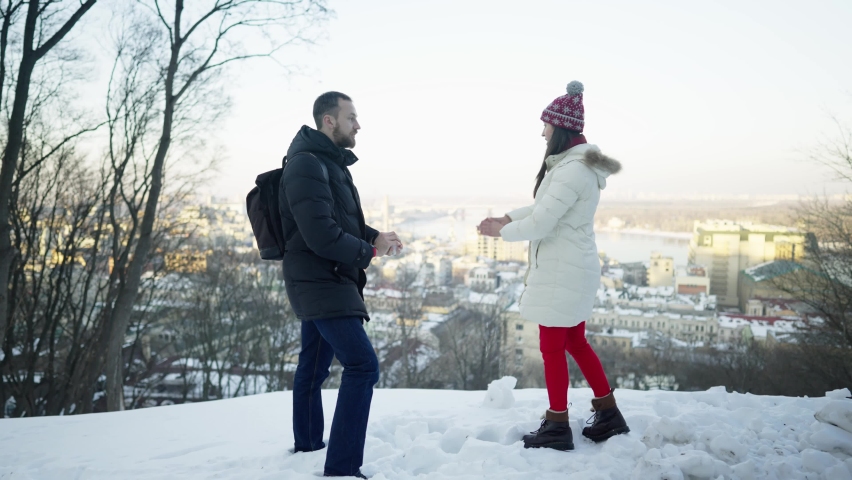 Happy romantic couple playing with snow at sunny winter day. snowball fights. Winter, sport, holidays, relationship, love, xmas, lifestyle concept. Filmed on cinema camera, 10 bit color space.