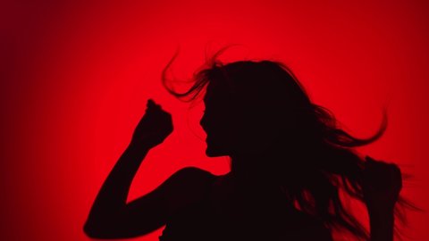 Portrait of black shadow dancer woman with waving hair dancing at red gradient studio. Pleasant seductive lady demonstrate modern dance movement relaxing enjoying freedom. Medium shot on RED camera