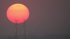 A large orange sun layer settles. Beautiful sunset, sunrise where the sun sets behind electric poles and antennas. - Powered by Shutterstock - Get 15% off with code: PIKWIZARD15