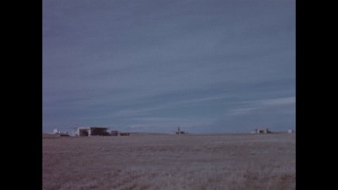 1960s: Military complex on barren ground. ICBM missile starts to raise behind building.