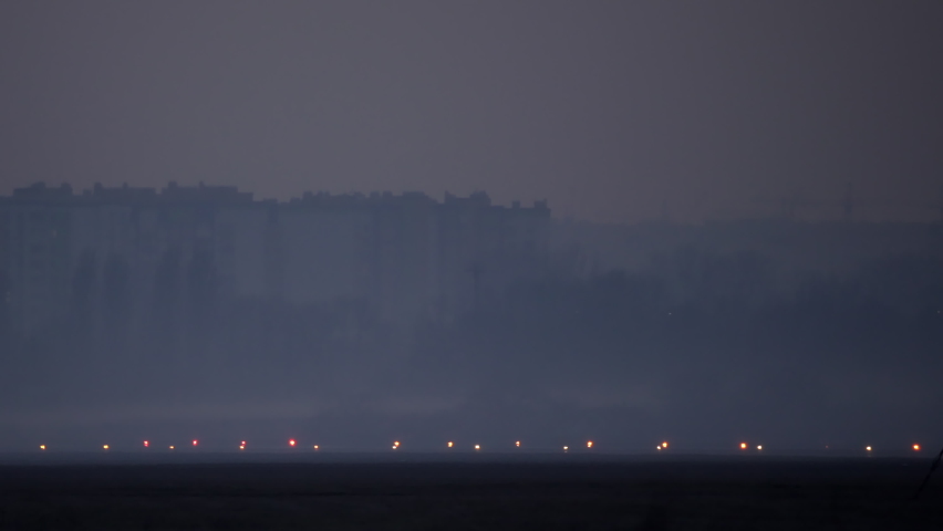 Evening airport plane takes off. Illuminated runway on which the plane takes off, and in the background of the city. Royalty-Free Stock Footage #1069803679