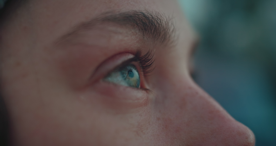 Close up of female eye. Authentic candid real woman in grey beanie hat stand outside in nature or on street, looking up at sky. Beautiful mindfulness concept. Human feelings and emotions