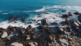 Aerial drone shot over the Chilean coast, cinematic and static stabilized video over the waves hitting the rocks aerial video and travel concept