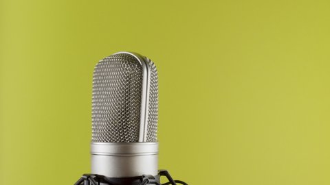Studio microphone on an anti vibration stand rotating. Professional audio recording equipment on yellow background.