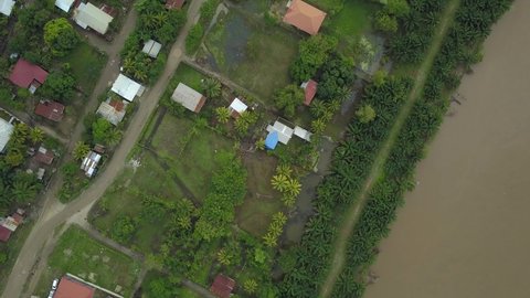 Birdseye of a small town next to a green forest and a brown river after a hurricane