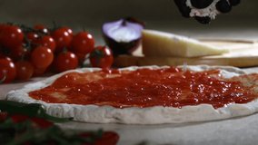 Making italian pizza in Napoli: Slow motion video of buffalo mozzarella cheese falling on an Italian margherita pizza with tomato sauce ready to cook in the wood oven