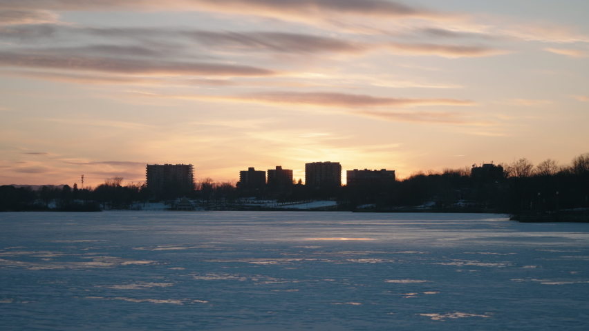 Silhouetted City With Frozen Lake Of Nations In Sherbrooke, Quebec, Canada During Sunset. - Static Wide Shot