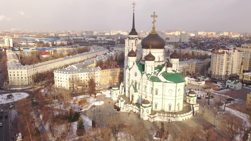 Aerial view of five-domed building of Annunciation Cathedral with attached bell tower in Voronezh on background with winter cityscape, Russia Royalty-Free Stock Footage #1069823668
