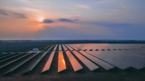 Timelapse aerial drone view of large solar panels at a solar farm at early spring sunset, sun in the sky with clouds. Solar cell power plants. footage video 4k. Green energy innovation concept.