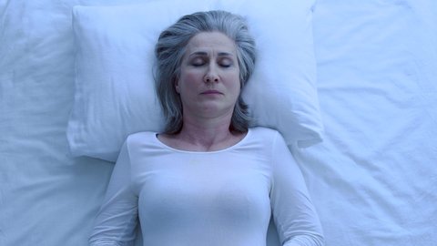 Worried greyhaired woman waking up at night, feeling anxious, scary nightmares