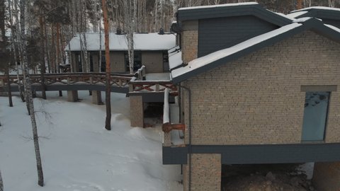 Hunting complex in the forest among snowy trees. Drone flyby in winter. Houses in a winter landscape.