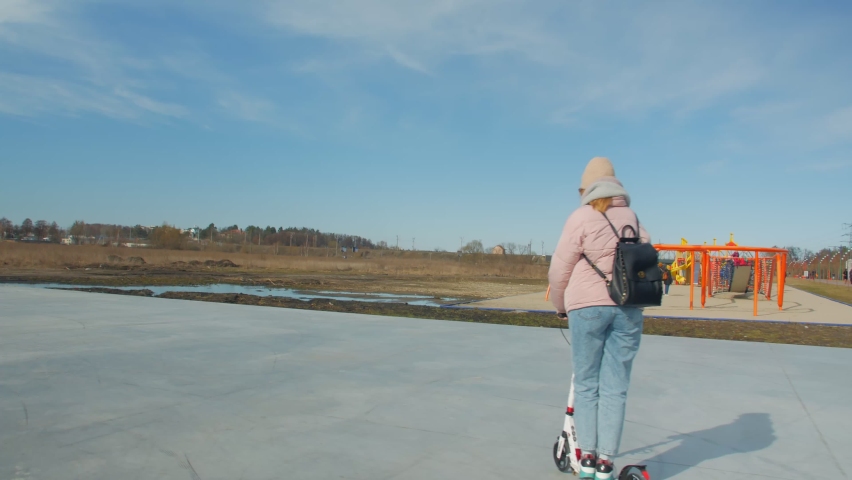 Woman on kick scooter on the playground in the park