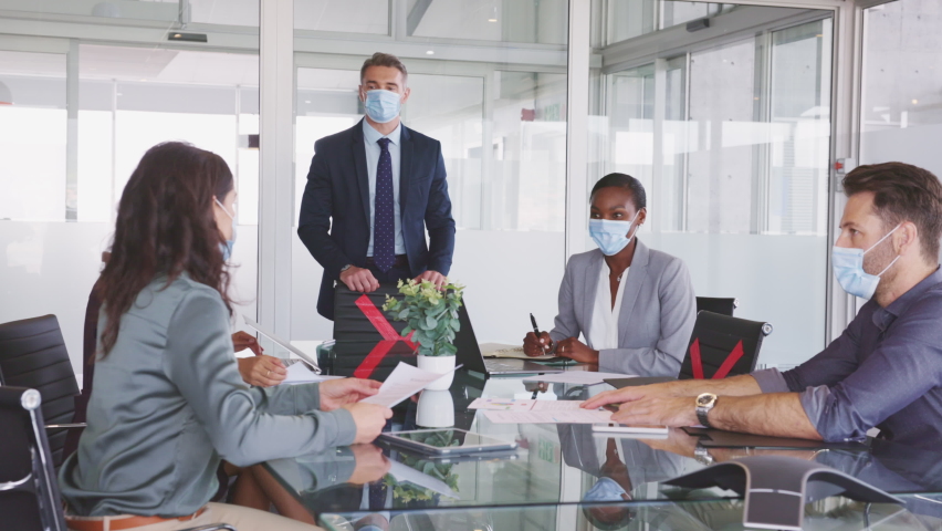 Group of multiethnic business people in meeting wearing face mask in conference room during covid19 pandemic. Business workers discussing strategy while wearing masks keeping social distancing. Royalty-Free Stock Footage #1069827943