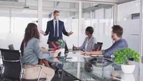 Mature businessman discussing project details with colleagues in modern office with face mask for safety against covid-19 virus. Business people brainstorming and discussing in conference room. - Powered by Shutterstock - Get 15% off with code: PIKWIZARD15