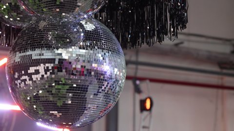 Silver Mirror Disco ball with bright rays, party with blurred background. Rotating disco mirror ball.