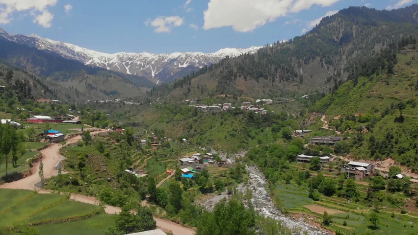 Aerial Over Road Through Swat Valley With Snow Capped Mountains In Distance. Tracking Shot Royalty-Free Stock Footage #1069837537