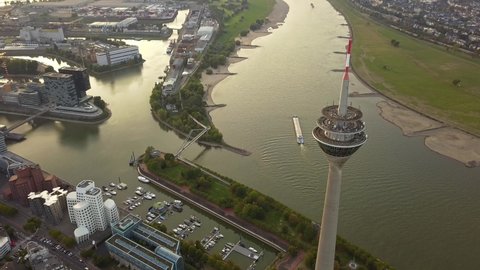Sunrise By The Rhine River In Dusseldorf, Germany. Aerial View Of The Iconic Rheinturm Overlooking Skyline Buildings By The Riverbank - tilt-up drone