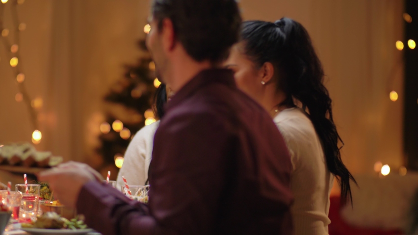 Winter holidays, celebration and people concept - happy friends having christmas dinner at home | Shutterstock HD Video #1069851367