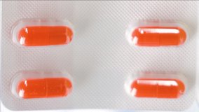 Orange capsules in one pack found in the laboratory with ten capsules on it in vertical video
