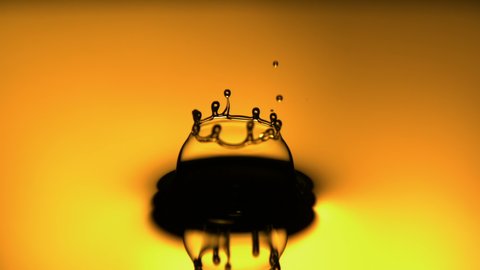 Droplet Falling in Slow Motion into a Yellow Liquid Creating a Crown