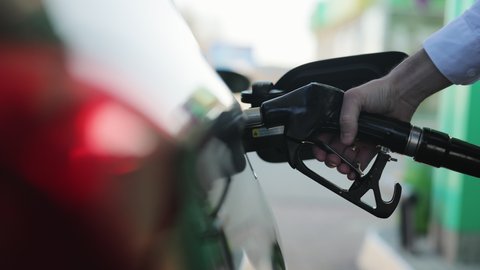 Refueling a car at a gas station. Hand holding and recording the process. Fuel, gas station, petrol prices concept. Gasoline, gas, fuel, petroleum concept. Filling car with gas fuel at station pump