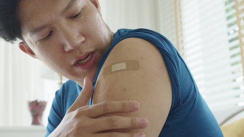 Close up young adult attractive hipster asia man receive covid-19 anti virus vaccine in campaign vaccination safe life got side effect pain at arm. Vaccine rollout swelling in volunteer.