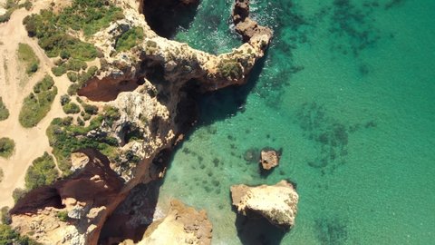 Golden cliff Escarpment opposing turquoise sea in Lagos, Algarve, Portugal - Aerial Bird's eye view fly-over shot